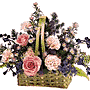A wicker basket with flowers such as Carnations, Delphinium, Monte Casino, Roses and Statice all in shades of pink, peach and lavender.