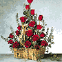 One dozen and a half Roses are arranged in a woven basket with assorted greenery and raffia for a little country charm